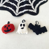 Halloween-themed plush toys including a pumpkin, ghost, and bat on a white background with a spiderweb design.