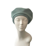 Green beanie on a mannequin head against a white background