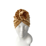 Gold velvet turban on a mannequin head against a white background