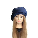 Mannequin head with long blonde hair wearing a navy blue beanie on a white background