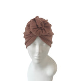 Brown knitted turban on a mannequin head against a white background