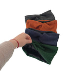 Hand holding a stack of folded ribbed knit scarves in various colors on a white background