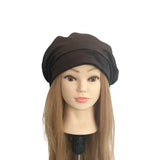 Mannequin head with brown hair wearing a black turban on a white background