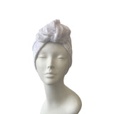 White textured head wrap on a mannequin head against a white background