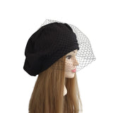Black beret with a mesh veil on a mannequin head against a white background