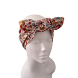 A multicolor patterned fabric headwrap styled on a white mannequin head against a plain white background.