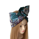 A patterned silk headwrap styled on a mannequin head with long light brown hair, set against a plain white background.