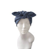 A navy blue fabric headwrap or turban with a large central bow, displayed on a white mannequin head and shoulders against a plain white background.