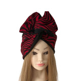 A large black and red zebra-striped fabric headwrap or turban hat displayed on a mannequin head with long light brown hair against a plain white background.
