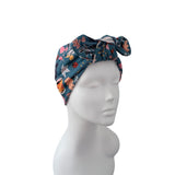 A multicolor butterfly-patterned fabric headwrap turban hat displayed on a white mannequin head against a solid white background.