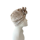 Beige headscarf with a flower on a mannequin head against a white background