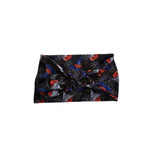 A black fabric headband with a twisted knot design, featuring a Halloween pattern of orange pumpkins, blue bats, and white spiderwebs on a plain white background.
