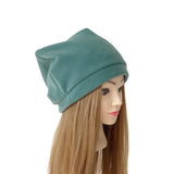 A teal green slouchy knit beanie hat displayed on a mannequin head with long light brown hair, set against a plain white background.