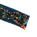 A close-up of a fabric headband with a dark navy blue base and a vibrant tropical floral print featuring orange, yellow, pink, and blue flowers on a black background.