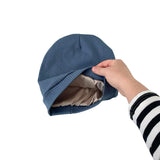 Blue beanie held by a hand against a white background