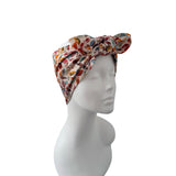 A multicolor patterned fabric headwrap turban hat displayed on a white mannequin head against a plain white background.