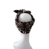A leopard print headband with a bow detail, displayed on a white mannequin head against a plain white background.