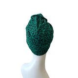 Green leopard print headscarf on a mannequin head against a white background