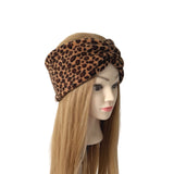 A leopard print twisted headband displayed on a mannequin head with long blonde hair, set against a plain white background.