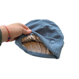 Hand holding a blue fabric item against a white background
