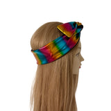 A metallic rainbow tie-dye headband with a large bow on top, displayed on a mannequin head with long blonde hair against a plain white background.