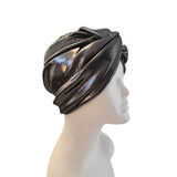 A metallic black headwrap turban hat displayed on a white mannequin head in profile against a plain white background.