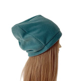 A teal fleece slouchy beanie hat shown on a mannequin head with long light brown hair, photographed against a solid white background.