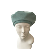 Green beret on a mannequin head against a white background