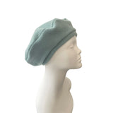 Light green beret on a mannequin head against a white background