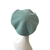 Green beret on a mannequin head against a white background