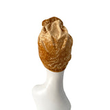 Brown textured headscarf on a white mannequin head against a white background