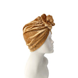 Gold velvet turban on a mannequin head against a white background