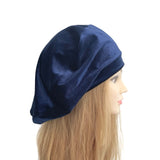Navy blue velvet beret hat on a mannequin head with blonde hair against a white background