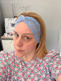 Person wearing a blue patterned headband in front of a sewing machine.