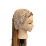 Mannequin head wearing a beige lace headscarf on a white background