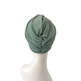 Green turban on a mannequin head against a white background