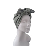 A ribbed fabric turban-style headwrap in a muted sage green color, displayed on a white mannequin head against a plain white background.