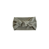 A ribbed fabric headband in a muted sage green color, featuring a knotted bow detail at the center front, presented on a solid white background.