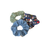 Three scrunchies in green, blue, and floral pattern on a white background