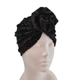 Black velvet turban with floral detail on a mannequin head against a white background