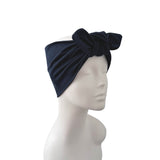 A dark navy blue fabric headwrap turban with a large bow on top, displayed on a white mannequin head against a plain white background.
