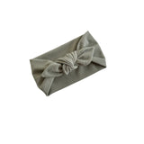 A light sage green fabric headband with a knotted bow detail, shown on a plain white background.