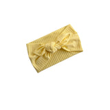 A pale yellow ribbed fabric headband with a knotted bow detail, displayed on a clean white background.