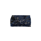 A navy blue fabric headband with a large twisted knot and an all-over gold floral pattern, shown against a plain white background.