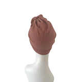 Brown knit turban on a white mannequin head against a white background