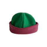 A soft fleece cuffed hat with a bright green crown and a contrasting dusty rose or mauve-pink folded cuff, shown against a plain white background.