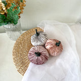 Decorative pumpkins on a woven mat with a vase of flowers in the background
