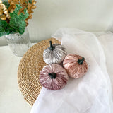 Decorative pumpkins on a woven mat with a vase of flowers in the background