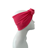 A bright pink textured headband with a twisted knot and rose detail, displayed on a white mannequin head in profile against a white background.