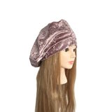Mannequin head with long brown hair wearing a pink velvet beret on a white background